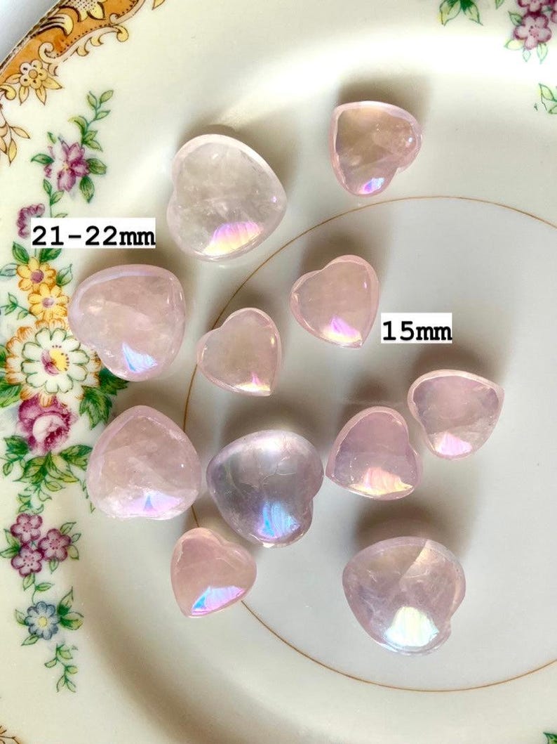 Translucent aura rose quartz hearts on a floral plate with sizes marked — dreamy pink crystals for emotional healing & heart-centered energy work