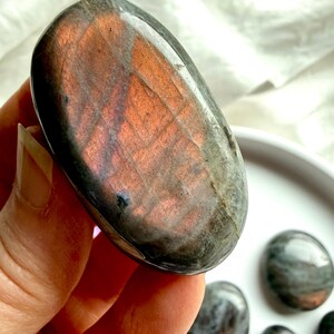 Peach Labradorite palm stone with warm pink and apricot flash held in hand