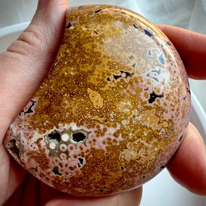 Peachy pink and yellow Ocean Jasper moon carving showing polished orbicular details and natural druzy accents