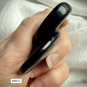 Size comparison of Black Obsidian worry stones held in hand – thumb stone for anxiety relief, grounding + chakra healing