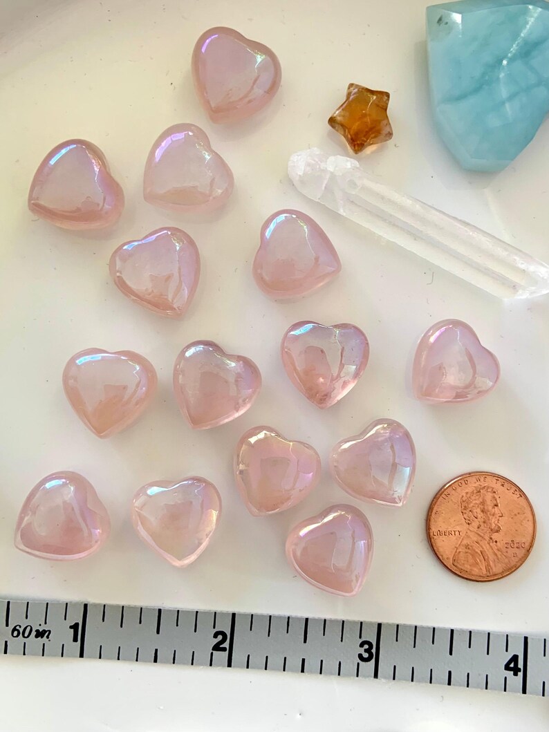 Mini angel aura rose quartz hearts shown with measuring tape & penny for size reference — glowing pink crystals for heart chakra healing & love
