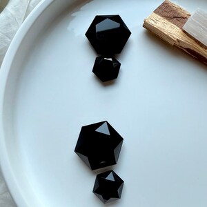 Black Obsidian faceted hexagon set showing size variations beside Palo Santo and Selenite — grounding protection stones for root chakra balance and clearing negativity.