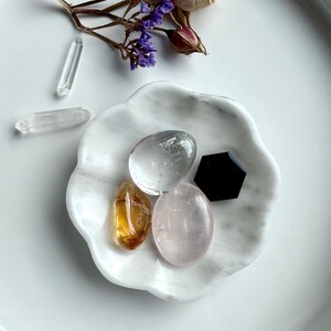 White marble daisy bowl styled with a mini crystal collection of rose quartz, clear quartz, citrine tumbles, with a black obsidian hexagon