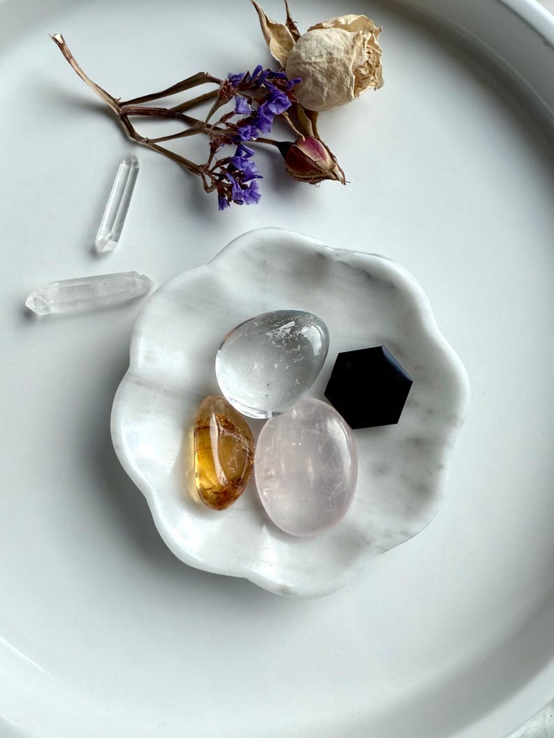 White marble daisy bowl styled with a mini crystal collection of rose quartz, clear quartz, citrine tumbles, with a black obsidian hexagon