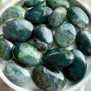 Polished moss agate palm stones showing natural green inclusions and earthy patterns, grounding crystals for stress relief