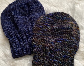 May include: Two knitted hats, one dark blue and one with a multi-colored pattern of blue, green, and brown.
