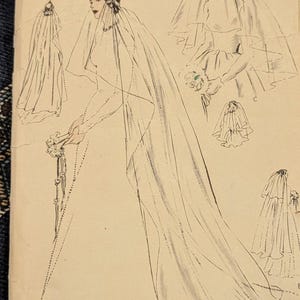 以下が含まれることがあります： ヴィンテージのVOGUE PATTERN封筒。黒いインクの線画で様々なブライダルベールとヘッドピースが描かれています。テキストにはVOGUE PATTERNおよびPrinted in U. S. A.と記載されています。イラストは、人物が身につけた様々な長さやスタイルのベールを描写しています。