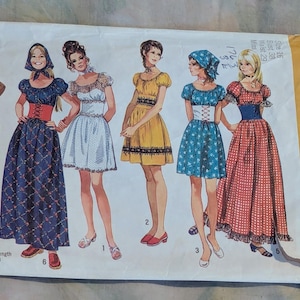 May include: Vintage Simplicity sewing pattern envelope featuring illustrations of six different dress designs. The dresses are in various colors and styles, with details like puff sleeves, fitted bodices, and full skirts. The envelope has the number 9164 and the price $1.00.