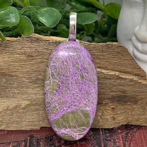 May include: An oval pendant with a silver bail, featuring a marbled pattern in shades of purple and green.