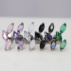 Peut inclure: Cinq styles différents de bijoux de corps en forme de feuille avec des accents de cristal. Chaque pièce présente un groupe de trois feuilles avec un seul cristal au centre de chaque feuille. Les cristaux sont de différentes couleurs, notamment rose, violet, blanc, noir et vert.