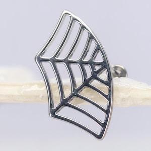 May include: A silver-toned metal earring featuring a fan-shaped spider web design with open cutouts. The piece has a polished finish and includes a standard post backing mechanism for attachment, showcasing a geometric and intricate web pattern.