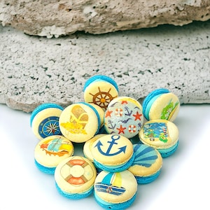 May include: A collection of nine blue and white macarons with nautical themed designs. The macarons are decorated with anchors, ships, steering wheels, and seashells.