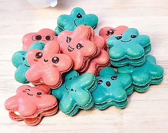 May include: A collection of pastel pink and blue star-shaped macarons with cute cartoon faces. The macarons are arranged in a pile on a light wood surface.