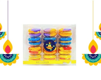 May include: A clear plastic box filled with colorful macarons. The macarons are arranged in rows and columns, with each macaron having a different color combination, including purple, blue, orange, and yellow. The box has a sticker with a candle design. The word "Macaron" is printed on the box.