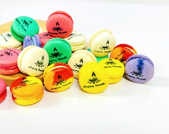 May include: Assortment of colorful macarons decorated with a Diwali-themed design. Each macaron features a small diya (oil lamp) and the text "Happy Diwali".