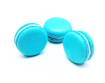 Può includere: Tre macarons blu con ripieno bianco. I macarons sono disposti a forma di triangolo su uno sfondo bianco.