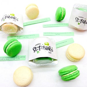 K&ouml;nnte beinhalten: Sortiment aus gr&uuml;nen und wei&szlig;en Macarons, verpackt in durchsichtigen Plastikbeh&auml;ltern mit Etiketten zum Thema St. Patrick's Day. Die Etiketten zeigen Kleebl&auml;tter und den Text "Happy St. Patrick's Day".