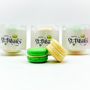 K&ouml;nnte beinhalten: Drei transparente Plastikboxen mit gr&uuml;nen, gelben und wei&szlig;en Macarons. Jede Box tr&auml;gt ein Etikett mit der Aufschrift "Happy St. Patrick's Day".