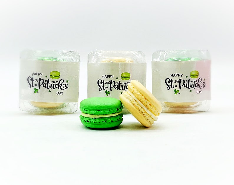 K&ouml;nnte beinhalten: Drei transparente Plastikboxen mit gr&uuml;nen, gelben und wei&szlig;en Macarons. Jede Box tr&auml;gt ein Etikett mit der Aufschrift "Happy St. Patrick's Day".