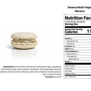 May include: A single sesame mochi vegan macaron with a light beige shell and a dark filling. The image includes a nutrition facts label with details like calories, fat, and sugar content. The ingredients list includes almond flour and black sesame.