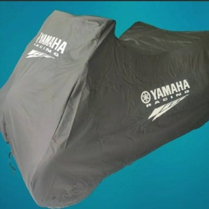 Op de afbeelding: Een motorfietsbeschermhoes in grijs en zwart. De hoes heeft aan beide zijden het Yamaha Racing-logo in het wit gedrukt. Ontworpen om een motorfiets te beschermen tegen de elementen.