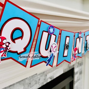 K&ouml;nnte beinhalten: Ein blaues und rotes Banner mit dem Namen "QUINION" in wei&szlig;en Buchstaben. Jeder Buchstabe hat einen schwarzen Umriss und ist mit einem Spinnen-Charakter verziert.