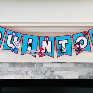 K&ouml;nnte beinhalten: Ein blaues und rotes Banner mit dem Namen "QUINTIN" in wei&szlig;en Buchstaben. An jedem Buchstaben ist ein kleiner Spiderman-Charakter befestigt.