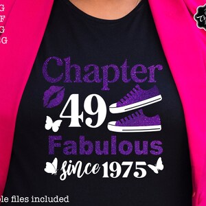 May include: A black t-shirt with purple glitter text that reads "Chapter 49 Fabulous since 1975". The text is surrounded by two purple glitter sneakers, a purple glitter lip print, and two purple glitter butterflies.