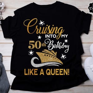 Pode incluir: Camiseta preta com texto dourado brilhante que diz "Cruising into my 50th Birthday like a Queen!". O design inclui um gr&aacute;fico de navio de cruzeiro. T&ecirc;nis brancos s&atilde;o vis&iacute;veis &agrave; direita. A camiseta &eacute; de estilo casual.