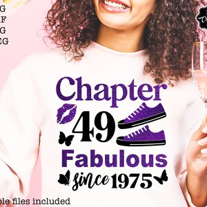 May include: Purple glitter text on a white shirt reads "Chapter 49 Fabulous since 1975".  Two purple glitter sneakers are above the text.  A purple glitter lip print is to the left of the number 49.  Two purple glitter butterflies are on either side of the year 1975.
