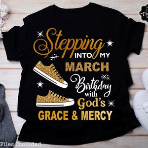 Może przedstawiać: Czarny T-shirt z napisem w złotym brokacie, kt&oacute;ry brzmi "Stepping into my March Birthday with God's Grace & Mercy". Po obu stronach napisu znajdują się dwie złote brokatowe trampki.