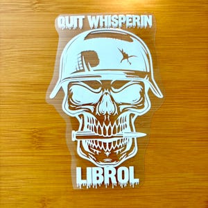 May include: White sticker featuring a skull wearing a military helmet with the text "QUIT WHISPERIN" above and "LIBROL" below. A knife is in the skull's mouth. The design is on a clear background.