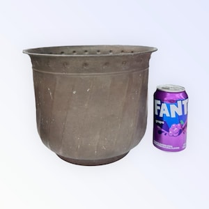 May include: A large, brown, metal planter with a textured, ribbed design. The planter is approximately the size of a standard can of soda.
