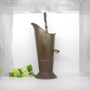 May include: A vintage copper coal scuttle with a wooden handle and brass accents. The scuttle has a hammered finish and a round base.