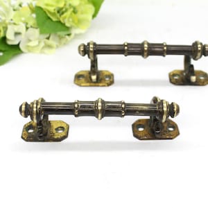 May include: Two antique brass door handles with a bamboo design. The handles have a square base with two holes for mounting.