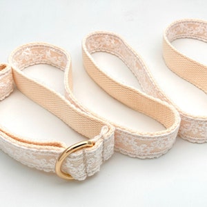 May include: A beige dog lead with white lace trim and a gold metal clasp.