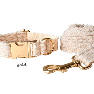 May include: A white lace dog collar and lead set with gold hardware. The collar has a gold buckle and the lead has a gold hook.