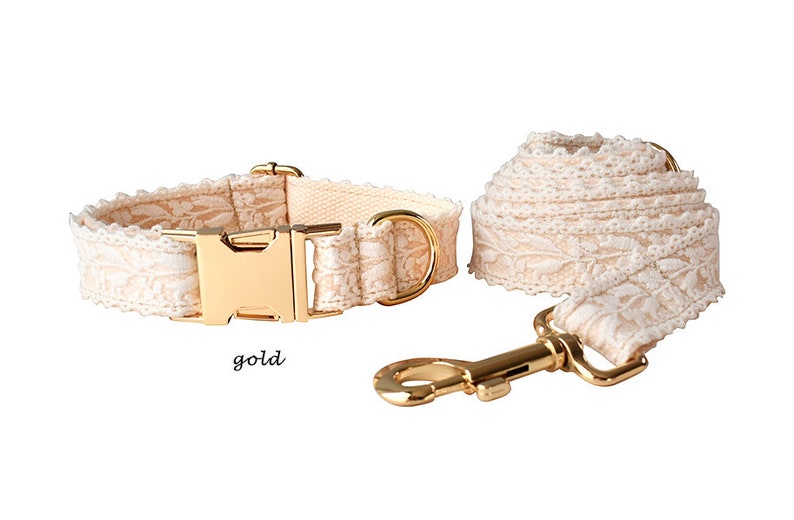 May include: A white lace dog collar and lead set with gold hardware. The collar has a gold buckle and the lead has a gold hook.