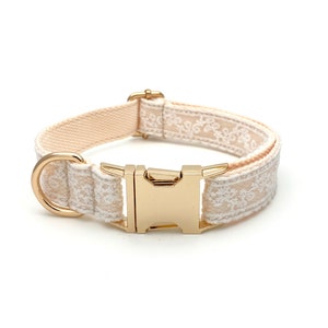 May include: A beige dog collar with a gold buckle and white embroidered floral pattern.