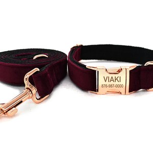 May include: Burgundy velvet dog collar and leash set with a rose gold buckle. The buckle has the text "VIAKI 876-987-0000" engraved on it.