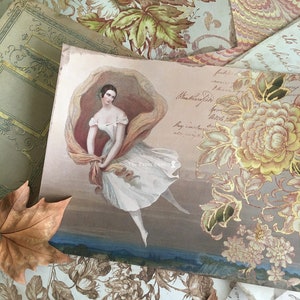 May include: An antique postcard featuring a watercolour illustration of a woman in a white dress and a flowing scarf, with the text "The Paper Cameo" at the bottom.