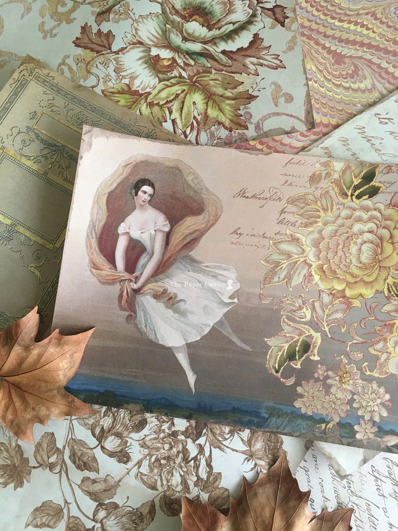 May include: An antique postcard featuring a watercolour illustration of a woman in a white dress and a flowing scarf, with the text "The Paper Cameo" at the bottom.