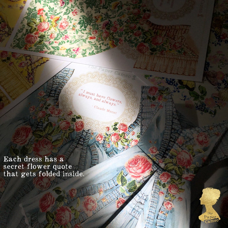 May include: A light blue paper dress with a floral design and the quote "I must have flowers, always, and always." by Claude Monet. The text "Each dress has a secret flower quote that gets folded inside." is also visible.