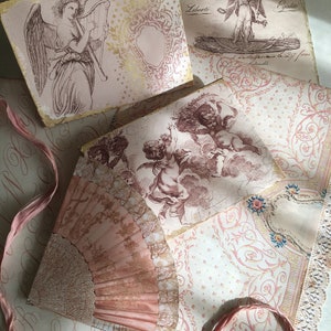 May include: A collection of vintage pink and gold paper ephemera with images of angels and cherubs. The paper is decorated with intricate patterns and designs. The paper is arranged in a layered fashion, creating a sense of depth and texture.