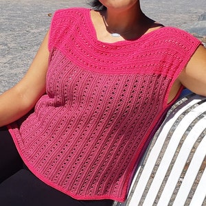 Könnte beinhalten: Ein pinkfarbenes, ärmelloses Häkeltop mit einem zarten Lochmuster. Das Top hat einen weiten, abgerundeten Ausschnitt und einen leicht ausgestellten Saum.