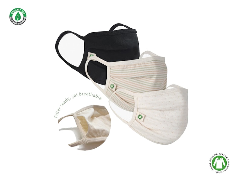 May include: Three reusable face masks made from organic cotton. The masks are in black, striped pink and beige, and white with small dots. Each mask has a filter pocket and a green GOTS certified logo.