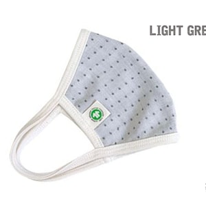 May include: Light grey face mask with white trim and small white polka dots. The mask has a white elastic band for the ears. The mask has a green logo with the text "Organic 100" and a leaf.