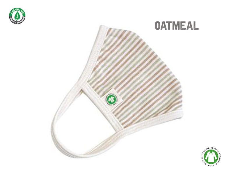 May include: A white and brown striped face mask with a green organic cotton logo. The mask is made of soft, breathable fabric and has adjustable ear loops. The text "OATMEAL" is printed in black above the mask.