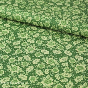 May include: Green fabric with a white floral pattern. The fabric is a cotton blend and is perfect for quilting, crafts, and home decor.