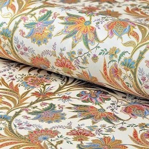 May include: A roll of wallpaper featuring a repeating pattern of intricate floral and botanical motifs in vibrant shades of orange, blue, green, and yellow set against a crisp white background, showcasing detailed petals and leaves.